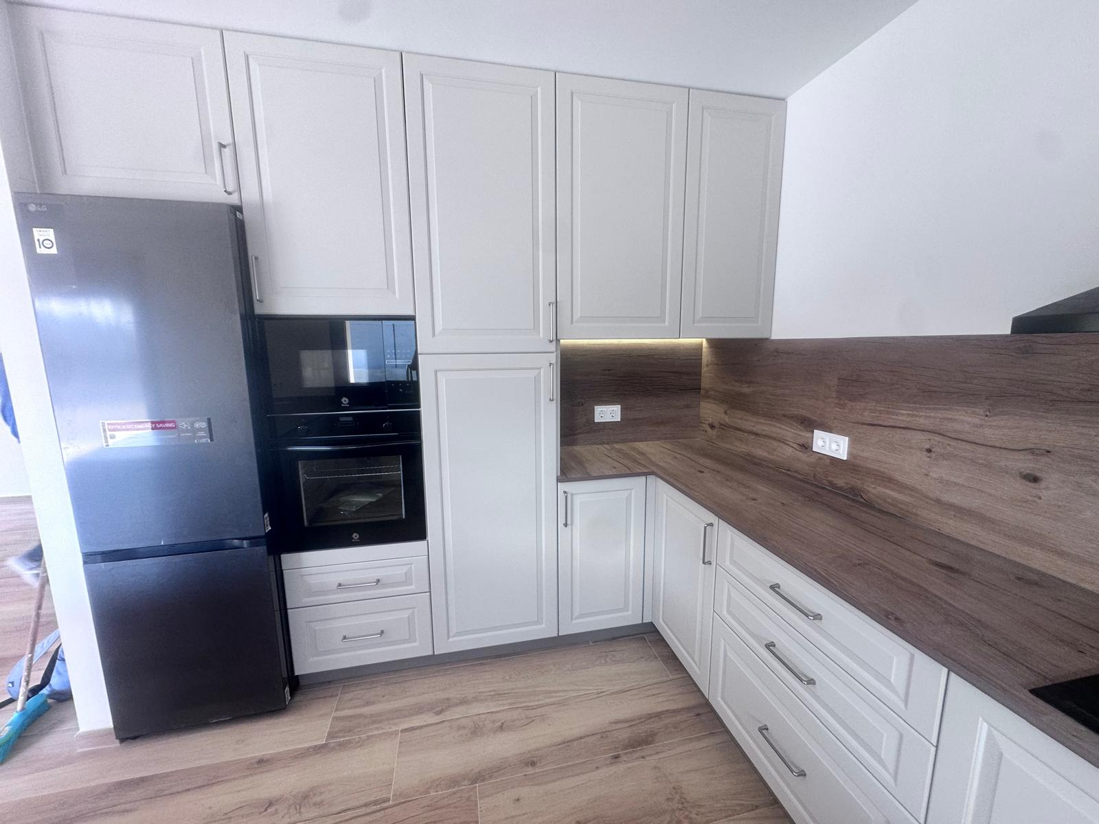 Cocina reformada con mobiliario blanco y encimera de madera